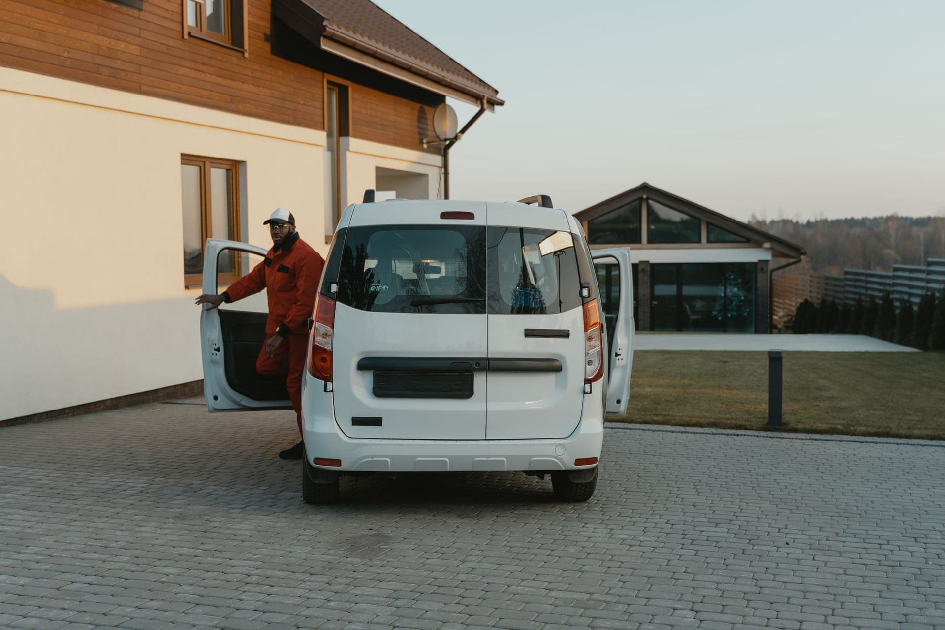 A service technician stepping out of his van in a customer's driveway for a booked appointment.