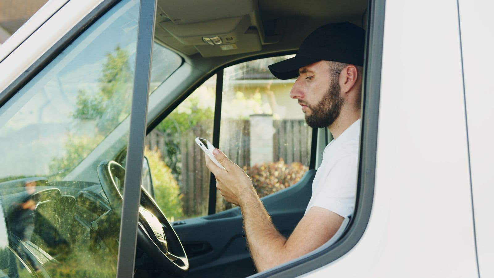 A tradesman sitting in his work van reading a text on his phone between jobs.