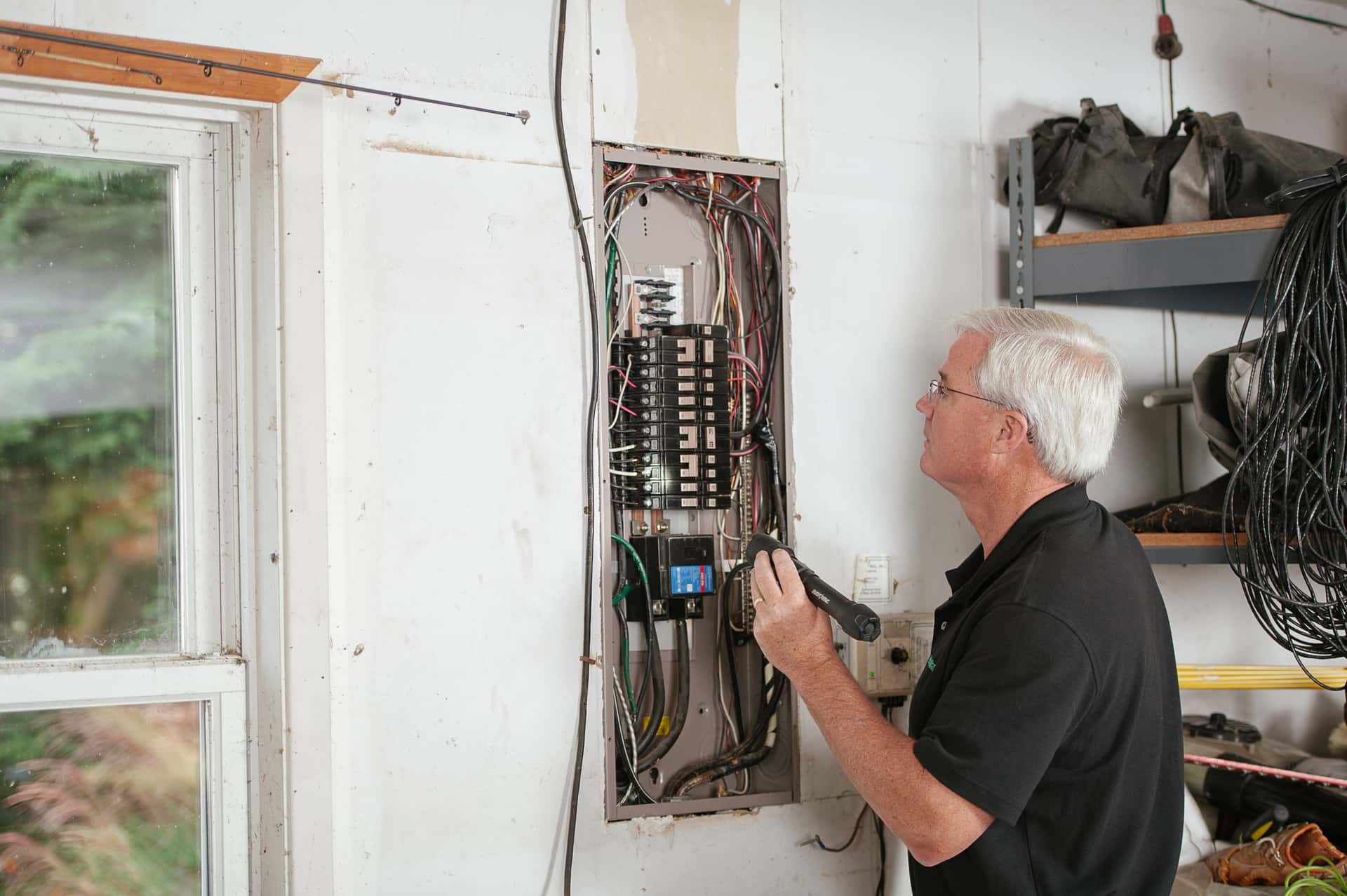 An electrician inspecting an open electrical panel
