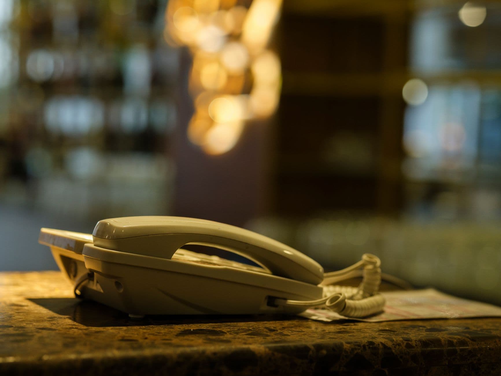 A corded desk phone sitting on a shop counter, the line most customers still call.
