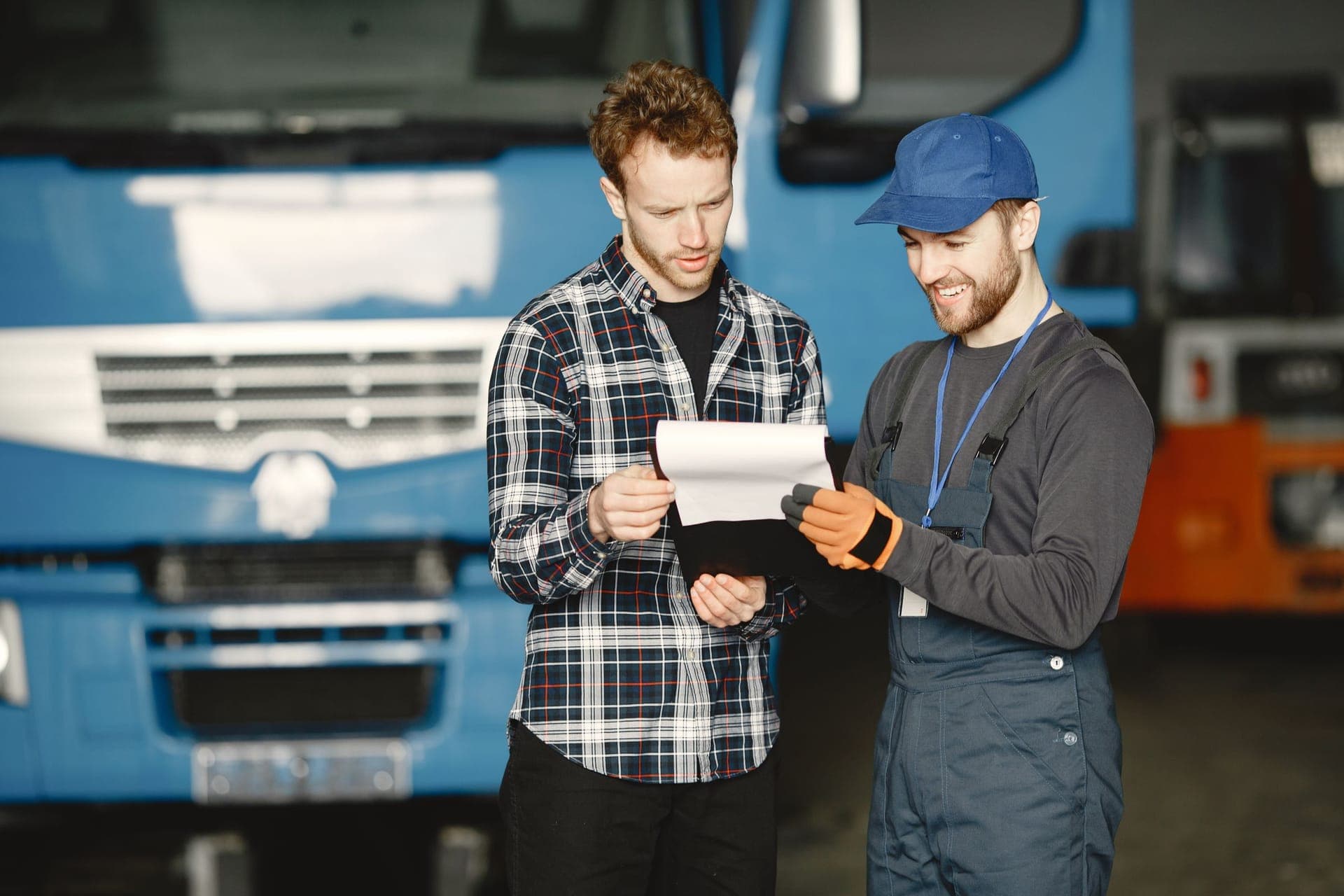 A shop owner and a technician going over paperwork and numbers in a service garage.