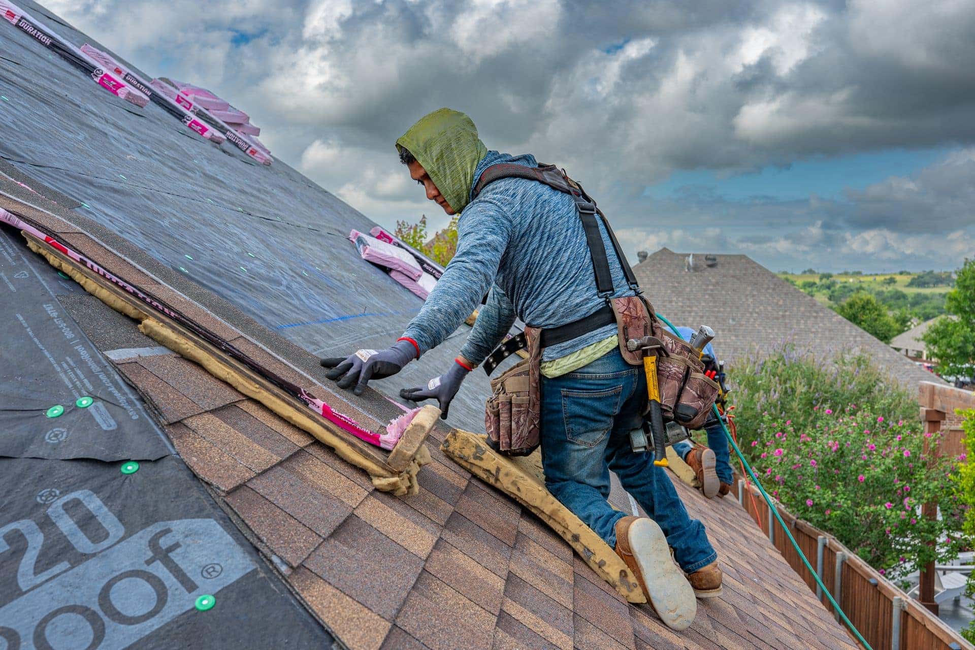 Roofers installing shingles on a home in Fort Worth, Texas on a clear day